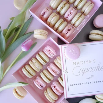 Two boxes of macarons with tulips around them, by Nadiya's Cupcakes